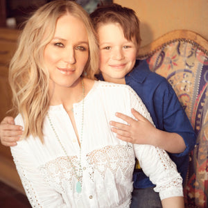 Singer Jewel with her son Kase as she models a long blue faceted chalcedony tear drop pendant on blue quartz and apatite bead chain